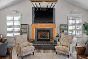 Gathering area featuring lofted ceiling, a tiled fireplace, and hidden television space.