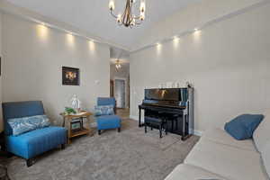Sitting room with a chandelier, carpet flooring, and vaulted ceiling