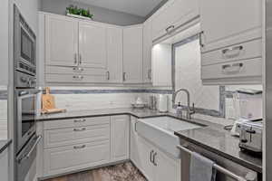 Kitchen featuring Quartz countertops, second sink, white cabinetry, and stainless steel appliances