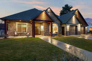 Craftsman inspired home featuring a front lawn, stone siding, a garage, and a shingled roof