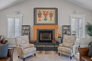 Gathering Room featuring vaulted ceiling, a fireplace, and wood finished floors - TV behind painting (65x52).