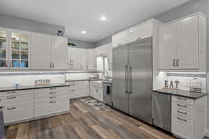 Kitchen with white cabinets, Quartzcountertops, backsplash, stainless steel appliances, and recessed lighting