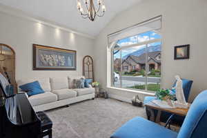 Carpeted sitting room featuring a chandelier, vaulted ceiling, and a mountain view