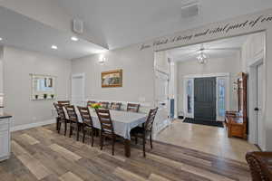 Dining area featuring recessed lighting, light wood finished floors, vaulted ceiling, and a chandelier