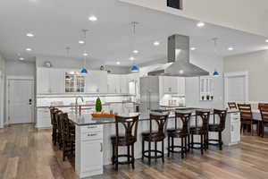 Kitchen featuring a breakfast bar, glass insert cabinets, dark stone countertops, hanging light fixtures, and white cabinetry