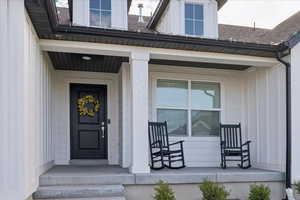 Entrance to property featuring a porch, board and batten siding, and roof with shingles
