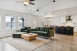 Living area with vaulted ceiling, light wood-style flooring, a chandelier, recessed lighting, and a ceiling fan