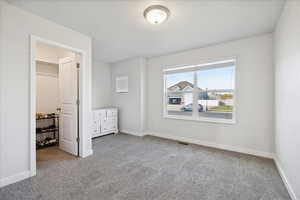 Unfurnished bedroom with light carpet and a spacious closet