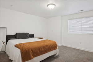 Carpeted bedroom with baseboards and a textured ceiling