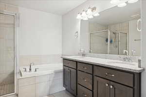 Bathroom with double vanity, a shower stall, light tile patterned floors, and a bath
