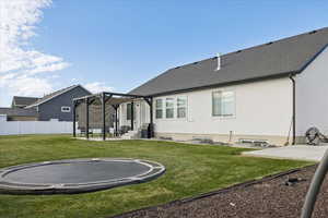 Back of house featuring a trampoline, a patio area, and stucco siding