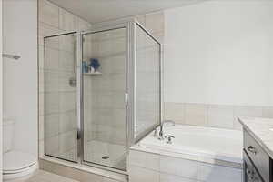 Full bath with vanity, a garden tub, a shower stall, tile patterned flooring, and a textured ceiling