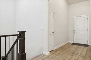 Hallway with light wood-style flooring and an upstairs landing