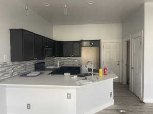 Kitchen featuring dark cabinetry, backsplash, black electric range, light wood-type flooring, and recessed lighting