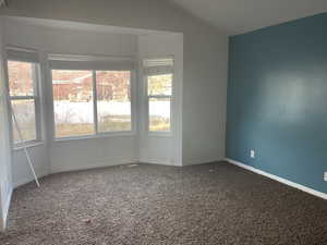 Spare room featuring carpet flooring and lofted ceiling