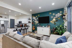 Living area with custom paint, large windows facing east, accent beams on the ceiling and hardwood flooring.