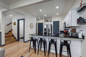 Kitchen with white cabinets, granite counters and bar seating.