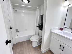 Full bathroom with shower / tub combo with curtain, vanity, and light wood flooring