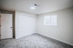 Unfurnished bedroom with light colored carpet and a closet