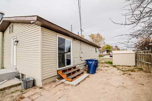 View of property exterior with entry steps and a shed