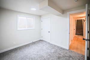 Unfurnished bedroom with light carpet, a closet, and a textured ceiling