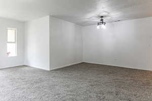 Carpeted spare room with a textured ceiling and a chandelier