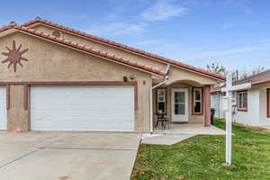 Mediterranean / spanish house featuring stucco siding, concrete driveway, a patio, an attached garage, and a front lawn