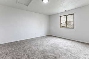 Carpeted empty room with a textured ceiling and baseboards