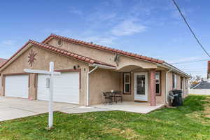 View of front of house featuring stucco siding, a patio, concrete driveway, and a front lawn