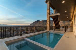 Twilight view of pool with spa, patio area, and valley mountain views