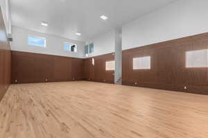 Sports court featuring regulation sized pickleball court and half-court basketball,  wainscoted wood walls, sport court flooring, wall mounted mini splits, and stairs to basement level 1