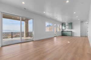Living area with entrance to deck with valley and mountain views, wet-bar, recessed lighting, and light wood-style floors