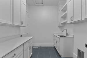 Washroom with dark tile patterned flooring, cabinet space, access from master suite closet and main level