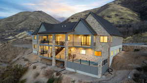 Back of property at dusk featuring pool, spa, stone siding, decks with valley and mountain views