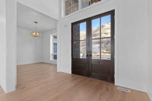 Foyer with light wood-type flooring, office chandelier, and main entrance french doors