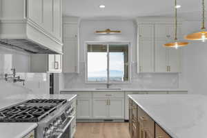 Kitchen with high end stainless steel range with oven, light stone counters, light wood-type flooring, recessed lighting, hanging light fixtures, and valley mountain view