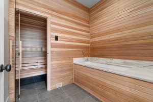 Relaxing cold plunge with sauna featuring tile patterned flooring and wood walls