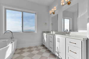Master Suite bath featuring double vanity, a freestanding tub, light tile floor, and valley mountain views