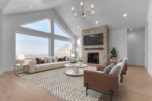 Living area with high vaulted ceiling, light wood finished floors, fireplace, chandelier, recessed lighting, and valley mountain views
