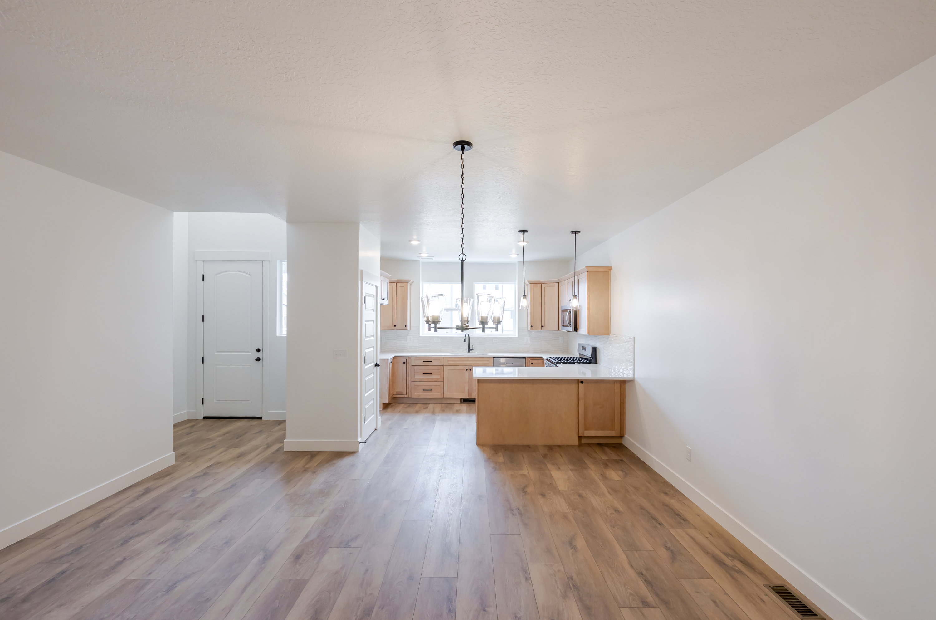 Kitchen featuring light wood finish cabinetry, light countertops, a peninsula, light wood-style flooring, and stainless steel gas range oven