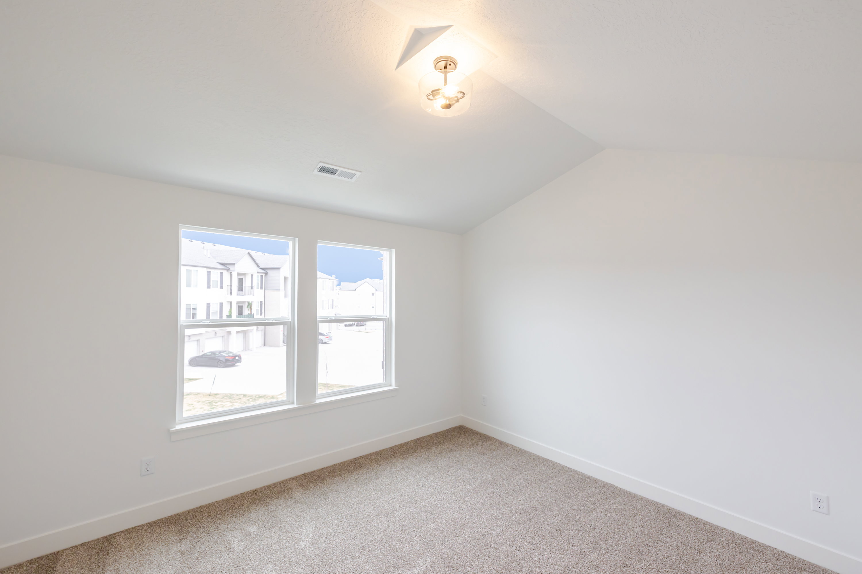 Spare room with light colored carpet and vaulted ceiling