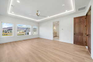 Unfurnished bedroom with a raised ceiling, light wood finished floors, a ceiling fan, and recessed lighting