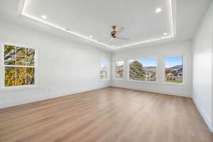 Unfurnished room with light wood-style floors, a raised ceiling, recessed lighting, and ceiling fan