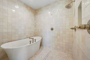 Full bathroom featuring tile walls, a soaking tub, and tiled shower