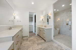 Full bath featuring recessed lighting, two vanities, a shower stall, light stone finish flooring, and a spacious closet