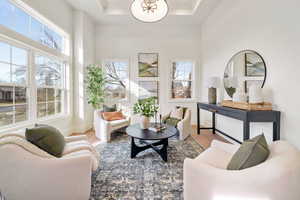 Sitting room with healthy amount of natural light, wood finished floors, and a tray ceiling