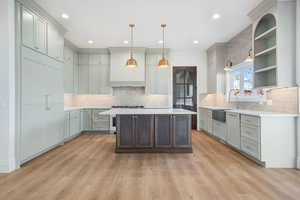 Kitchen featuring a kitchen island, open shelves, decorative light fixtures, gray cabinetry, and light wood-style floors