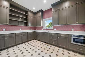 Kitchen featuring open shelves, light flooring, recessed lighting, stainless steel oven, and light stone countertops