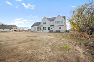 Rear view of house with a patio area, a mountain view, and stone siding