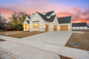 Modern farmhouse style home with concrete driveway, stone siding, stucco siding, and roof with shingles